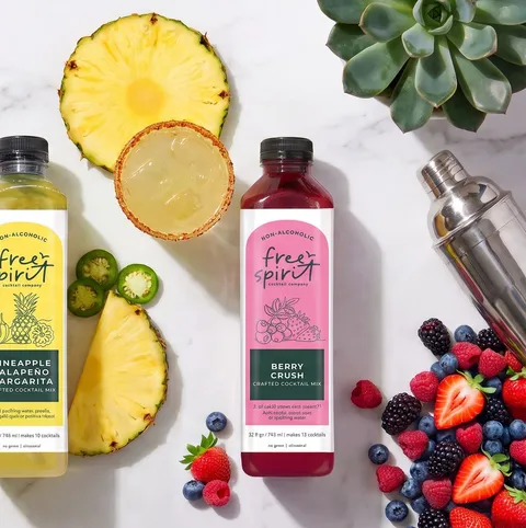 Pineapple Jalapeño Margarita and Berry Crush bottles with fresh pineapple, jalapeño and berries on marble